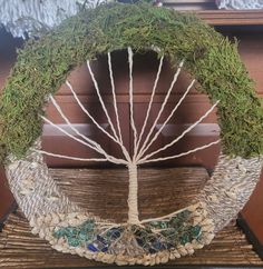 a tree made out of rocks and grass on top of a wooden table next to a window