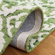 a green rug with white and gray designs on the bottom is laying on top of a wooden floor