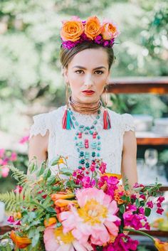 a woman with flowers in her hair wearing a necklace and holding a bouquet of flowers