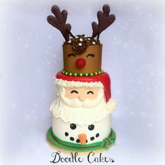 a three tiered cake decorated with santa claus and reindeer antlers on it's head