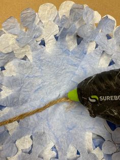 a black and green bottle on top of blue paper with a string attached to it