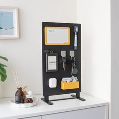 a black and yellow holder holds keys, cards, and other personal items on a white table