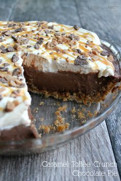 a chocolate pie with white frosting and chopped nuts on top sits on a wooden table