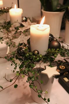 candles are lit on the table with greenery