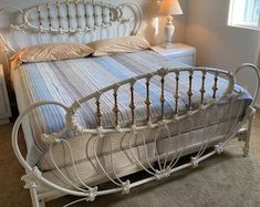 a white metal bed sitting in a bedroom next to a night stand with two lamps on top of it