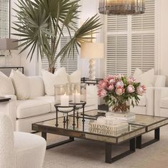 a living room filled with white furniture and lots of flowers on top of a coffee table