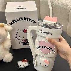 the hello kitty coffee mug is next to a stuffed animal