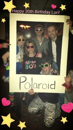 a group of people posing for a photo with a polaroid sign in front of them