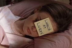 a woman laying in bed with a sticky note on her face