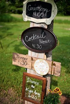 a sign that is on the side of a pole in front of some grass and flowers