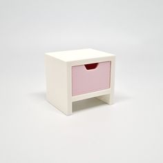 a small white box with a pink drawer on it's side, against a white background