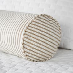 a white and brown striped pillow sitting on top of a bed