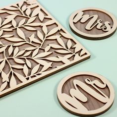 two wooden coasters with initials and leaves on them, sitting next to each other