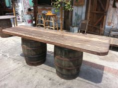 two wooden barrels sitting on top of each other in front of a building with chairs and tables