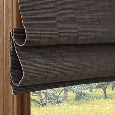 a close up of a window with blinds in the shade and flowers outside it,