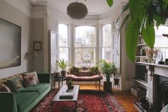 a living room filled with furniture and lots of plants on top of wooden flooring