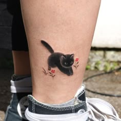 a black cat with red flowers on it's leg is seen from the side