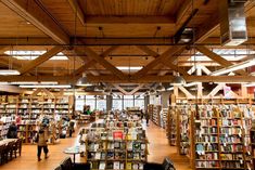 the inside of a library filled with lots of books and people walking around it,