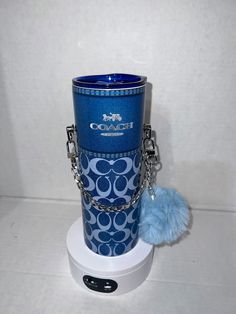 a blue cup sitting on top of a white table next to a keychain