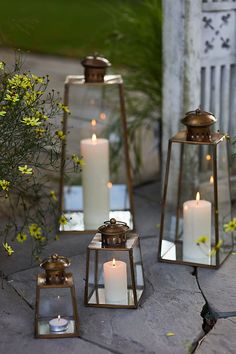 three lanterns with lit candles are sitting on the ground