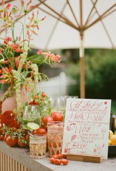 a table topped with lots of different types of fruits and vegetables next to a sign