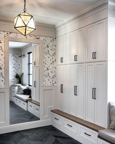 a room with white cupboards and black flooring next to a large window in the corner