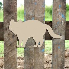 a wooden cutout of a cat on a fence with grass in the back ground