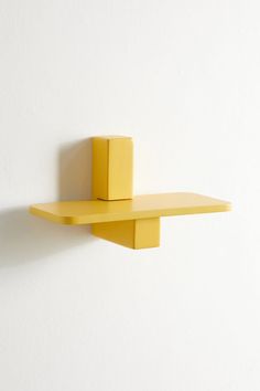 a yellow shelf on the wall with a white background