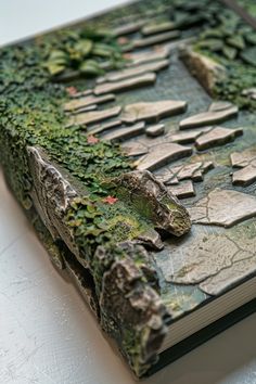 a book covered in moss and rocks on top of a table