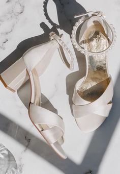 a pair of white high heeled shoes sitting on top of a marble countertop