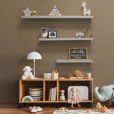 there is a toy elephant sitting on the floor next to a book shelf with books and toys