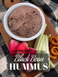 black bean hummus with celery and onion on a cutting board next to pretzels