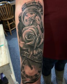 a person with a tattoo on their arm holding a clock and rose in the middle