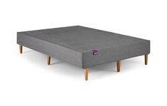 an upholstered bed frame with wooden legs and a mattress on it's side