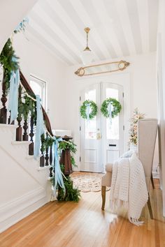 an entryway decorated for christmas with wreaths and garland on the bannisters