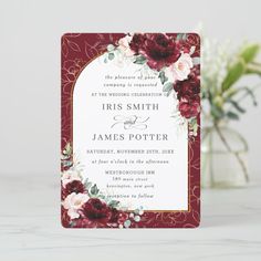 a red and white wedding card with flowers on the front is shown next to a vase