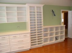 an empty room with white bookcases and drawers