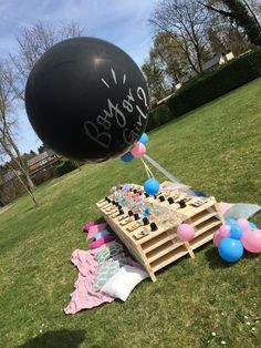 a large black balloon is in the air above a table with balloons and confetti