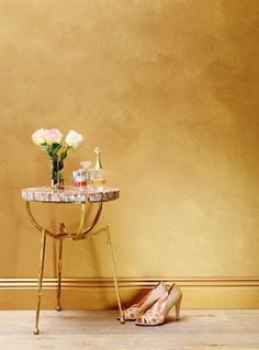 a pair of high heeled shoes sitting next to a table with flowers on it