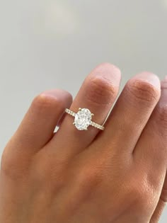 a woman's hand with a diamond ring on top of her finger and an engagement band