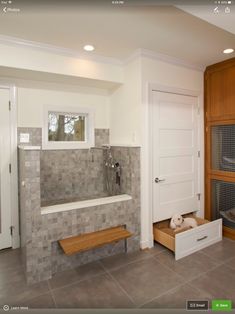 a bathroom with tiled walls and flooring next to a wooden shelf filled with towels