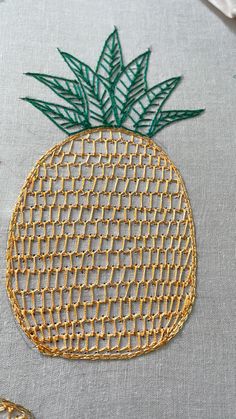 an embroidered pineapple is shown on the back of a piece of cloth with gold thread