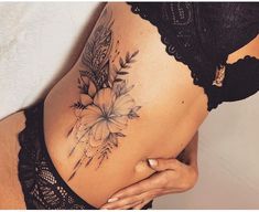 a woman's stomach with flowers and leaves tattooed on the side by her belly