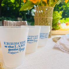 three frosted cups sitting on top of a table next to a vase with flowers in it