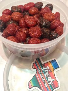 a plastic bowl filled with fruit sitting on top of a table next to a sticker