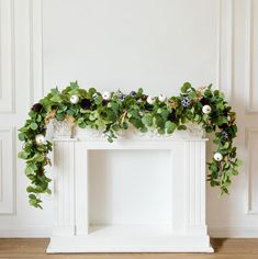 a fireplace decorated with greenery and white balls