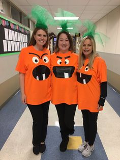 three women in orange shirts with green hair and faces on them standing next to each other