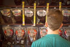 a man standing in front of a shelf filled with packaged food and bags of dried meat