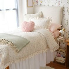 a bed with white sheets and pink pillows on top of it next to a window