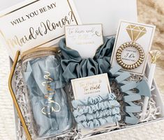 a gift box filled with blue items and congratulations cards on top of a white blanket